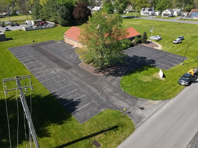 Curved residential asphalt driveway with freshly applied professional sealcoating