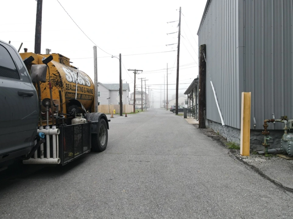 Industrial paving project with freshly installed asphalt driveway and heavy paving equipment.